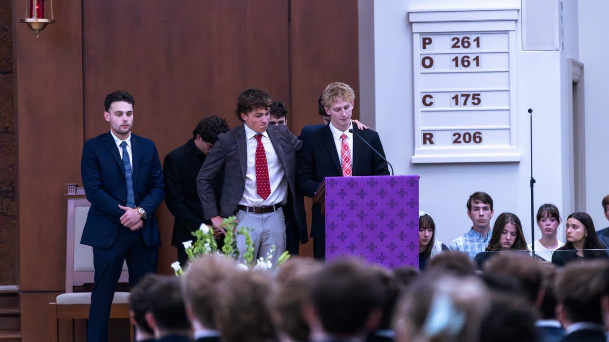 Young men in suits stand behind lectern in Catholic church after mass