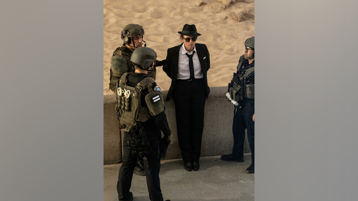 Suspect in suit and hat detained by officers during Hermosa Beach SWAT standoff