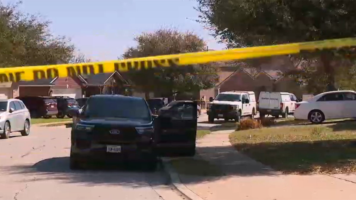police tape and cars surround a suburban home