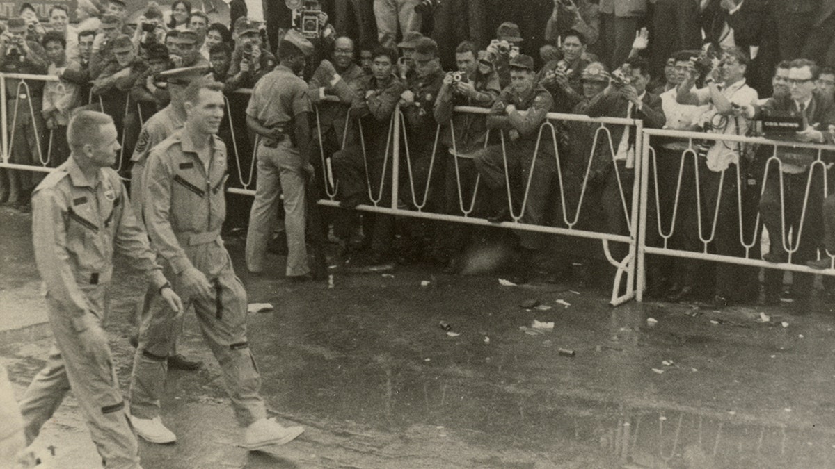 Neil Armstrong and astronaut David Scott walking by service members