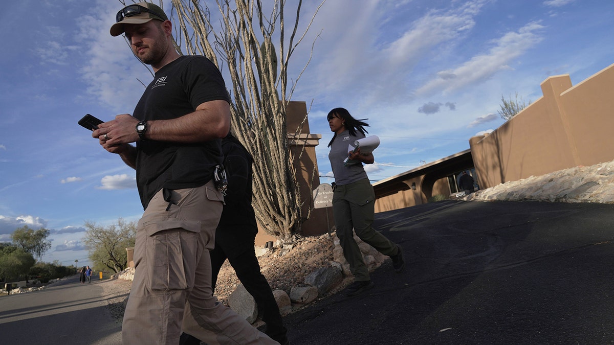 Investigators walking past houses and through a neighborhood in search of Nancy Guthrie