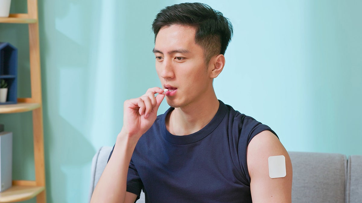 Closeup asian man quits cigarette - he puts a smoking cessation patch on his arm and chewing nicotine gum