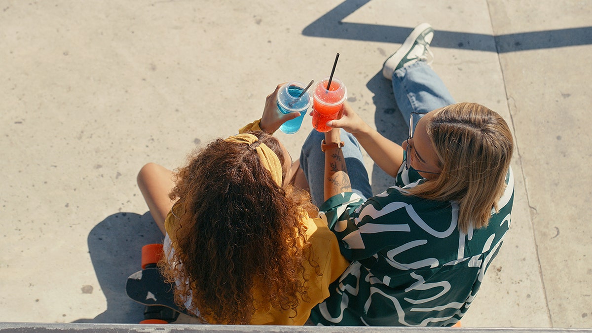 girls cheers colorful drinks outside