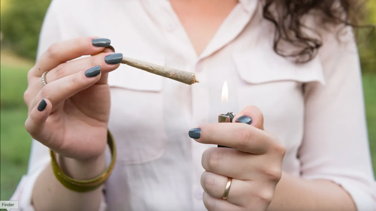 Woman lighting cannabis marijuana joint