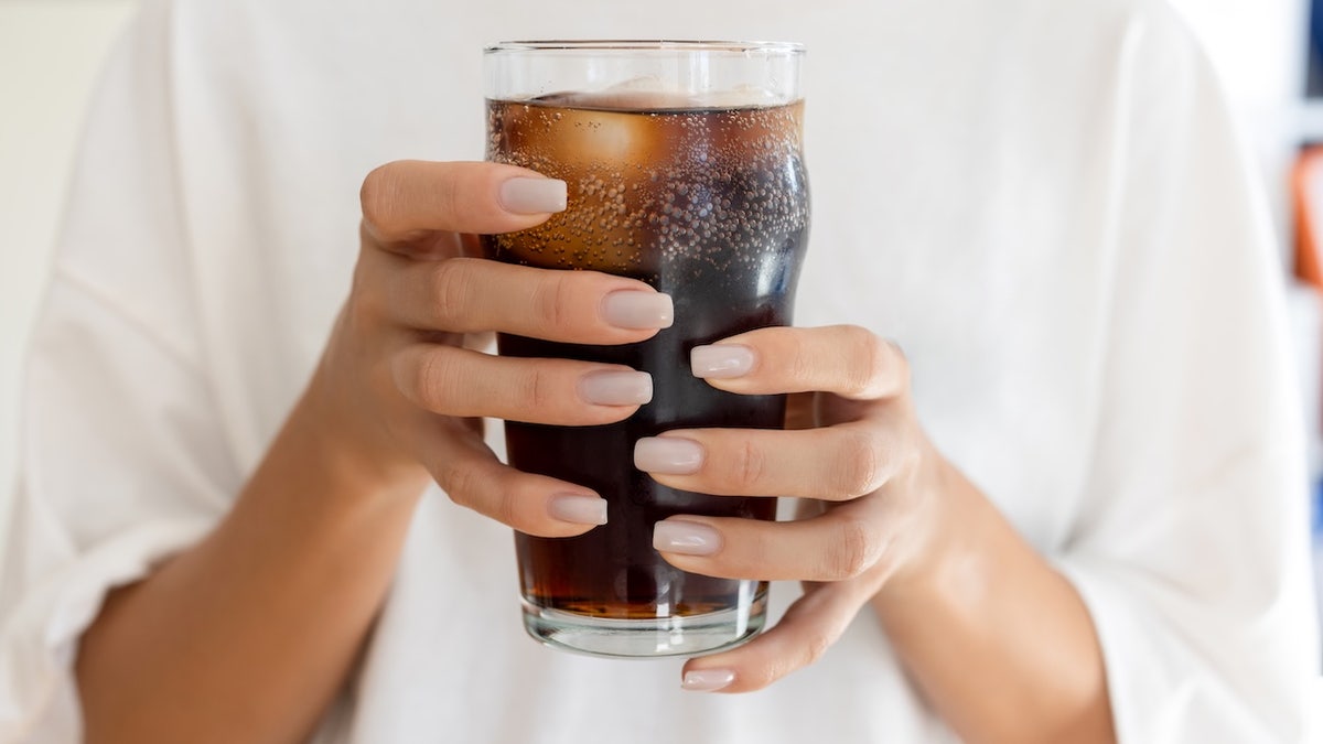 Woman holding soda in glass