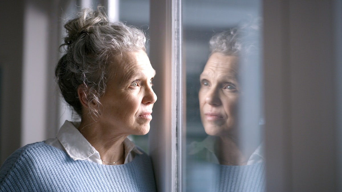 Woman looking out window feeling sad or confused