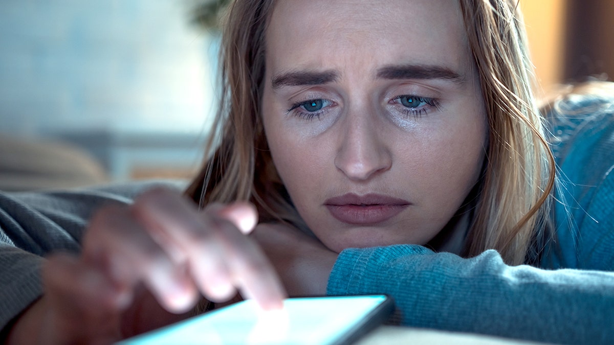 sad woman scrolls on phone