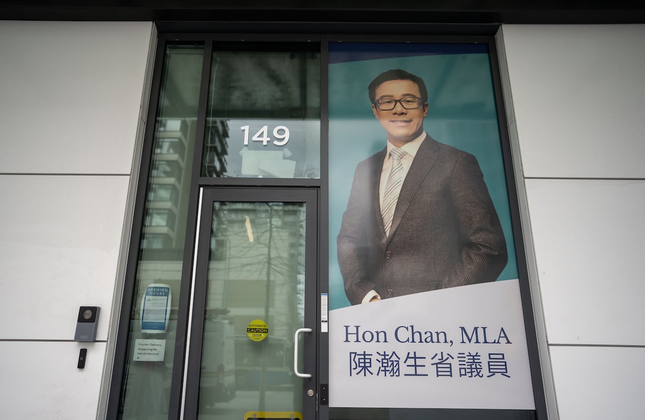 The front of an office with a large photo of a man beside the glass door.