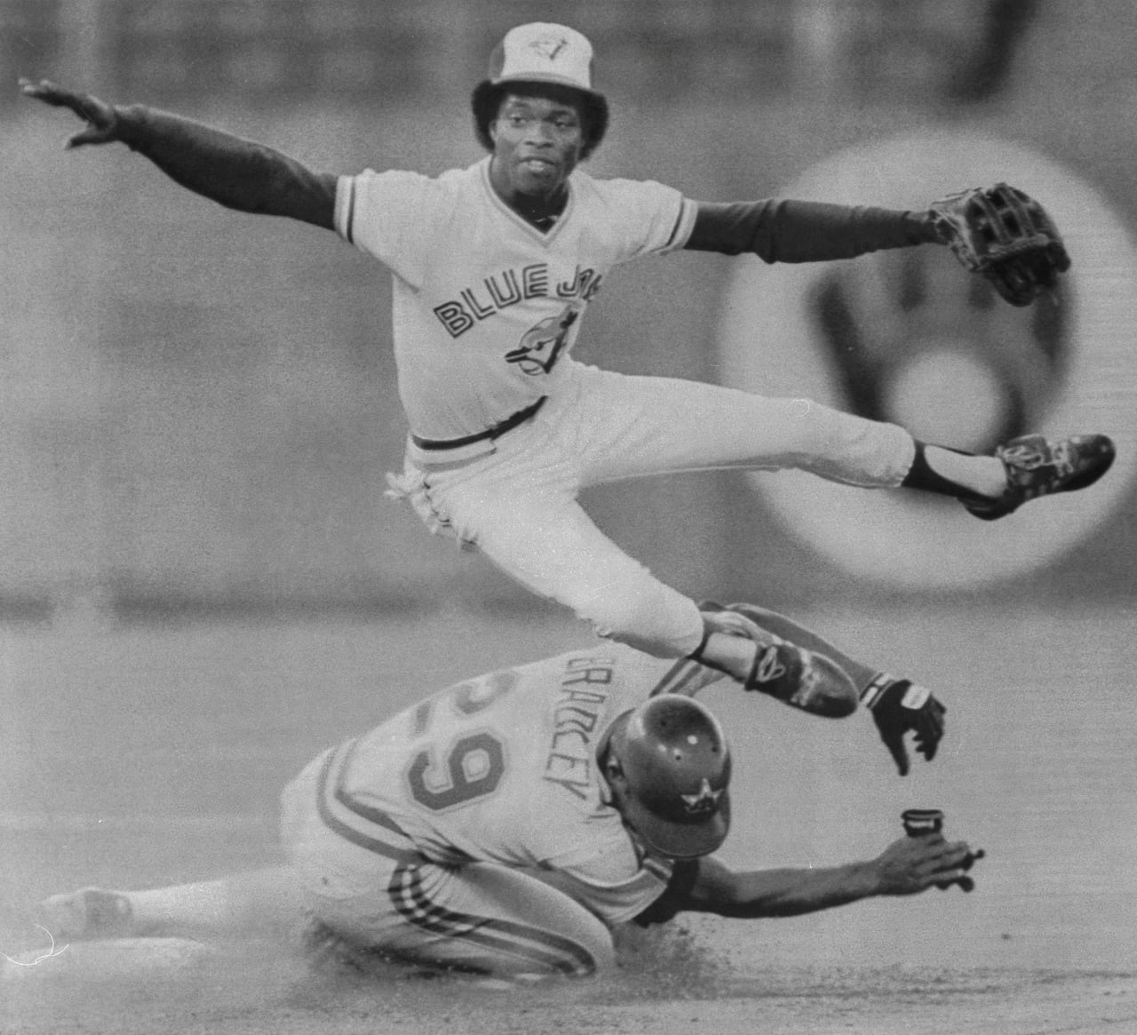 A photo of Blue Jays infielder Tony Fernández leaping over a sliding runner