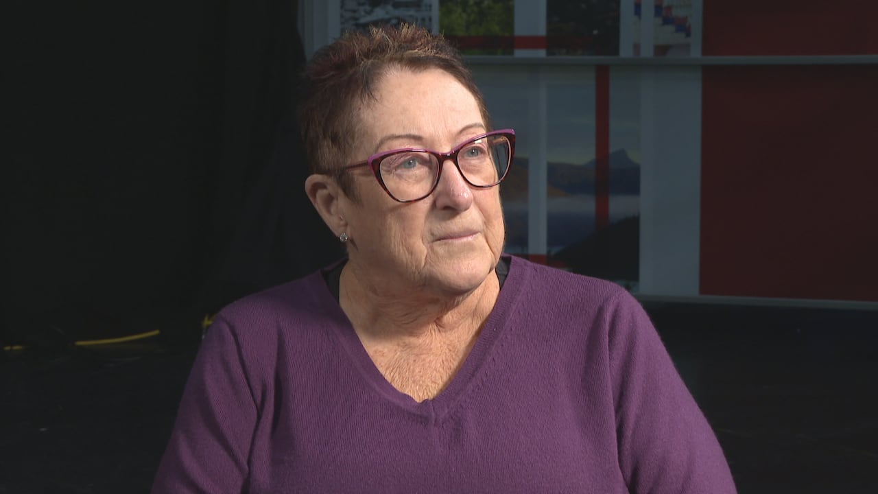 A woman in a purple shirt and glasses.