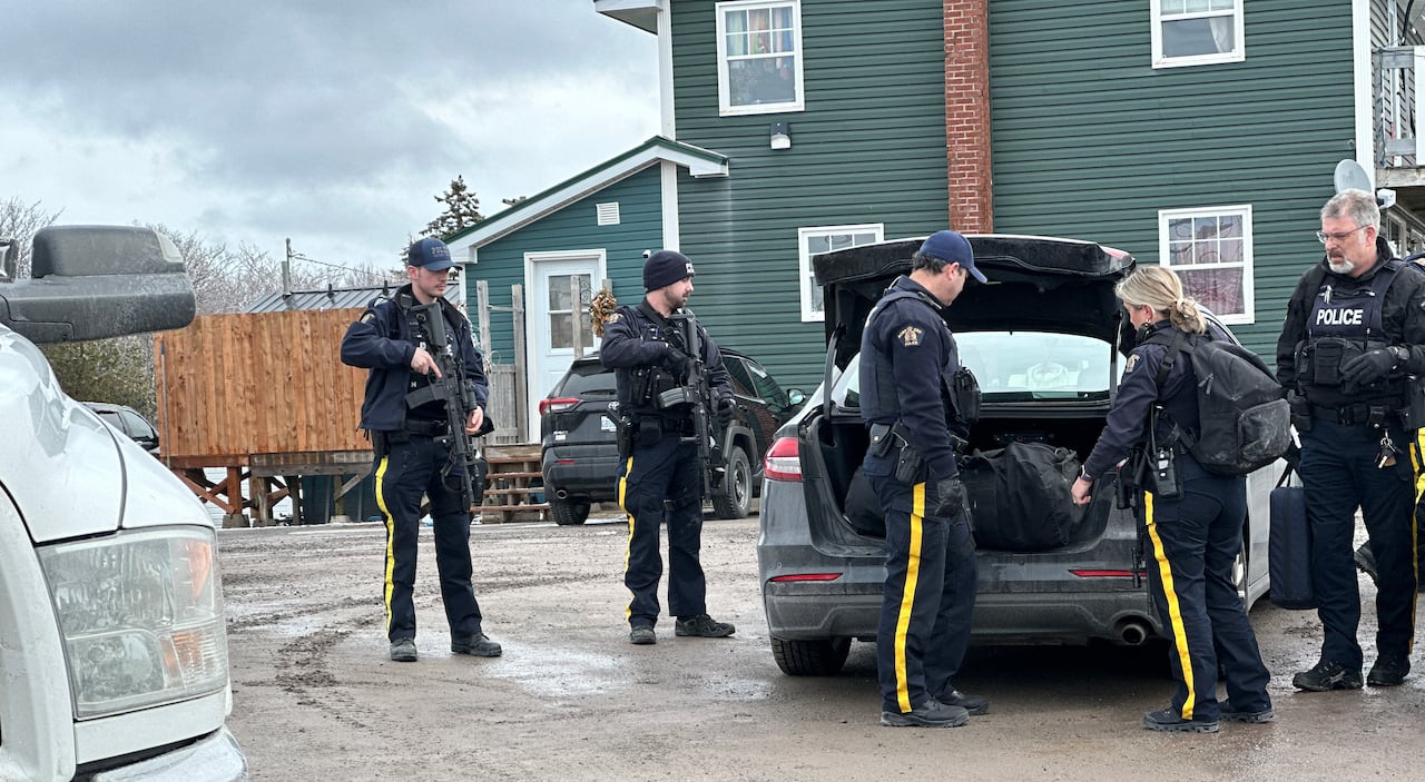 Five RCMP officers in uniform are seen carrying equipment and weapons 
