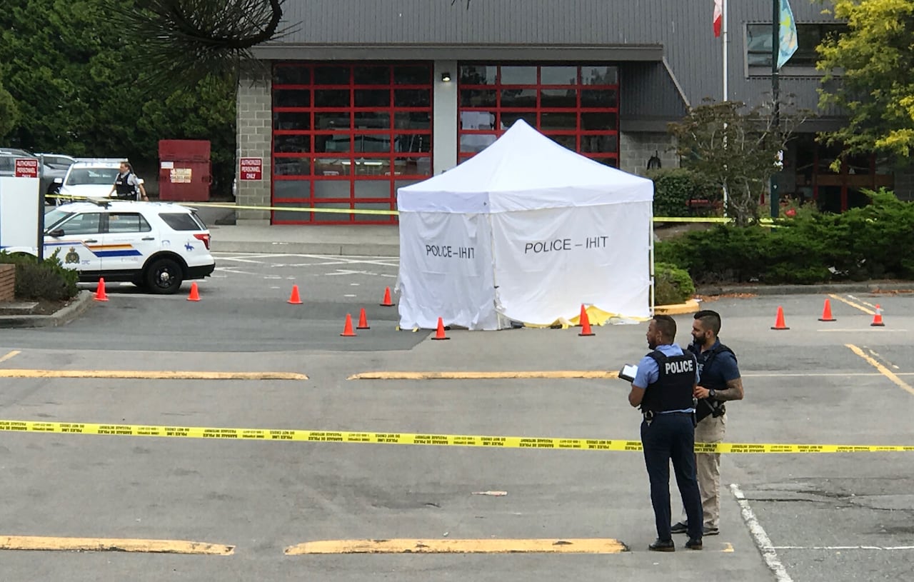 A police crime seen with a white tent set up on a parking lot and yellow tape blocking it off.