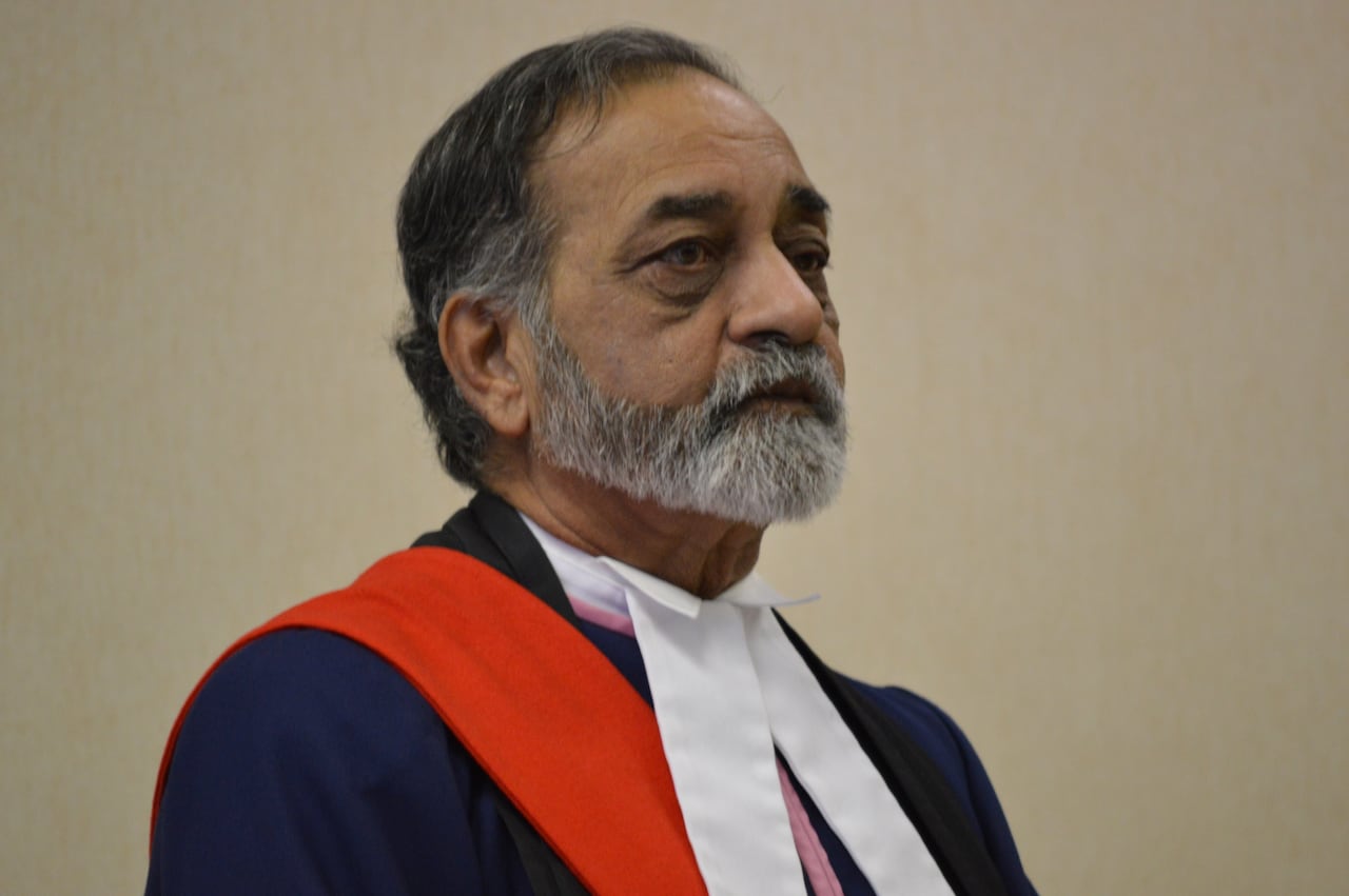 A judge in robes looks straight ahead