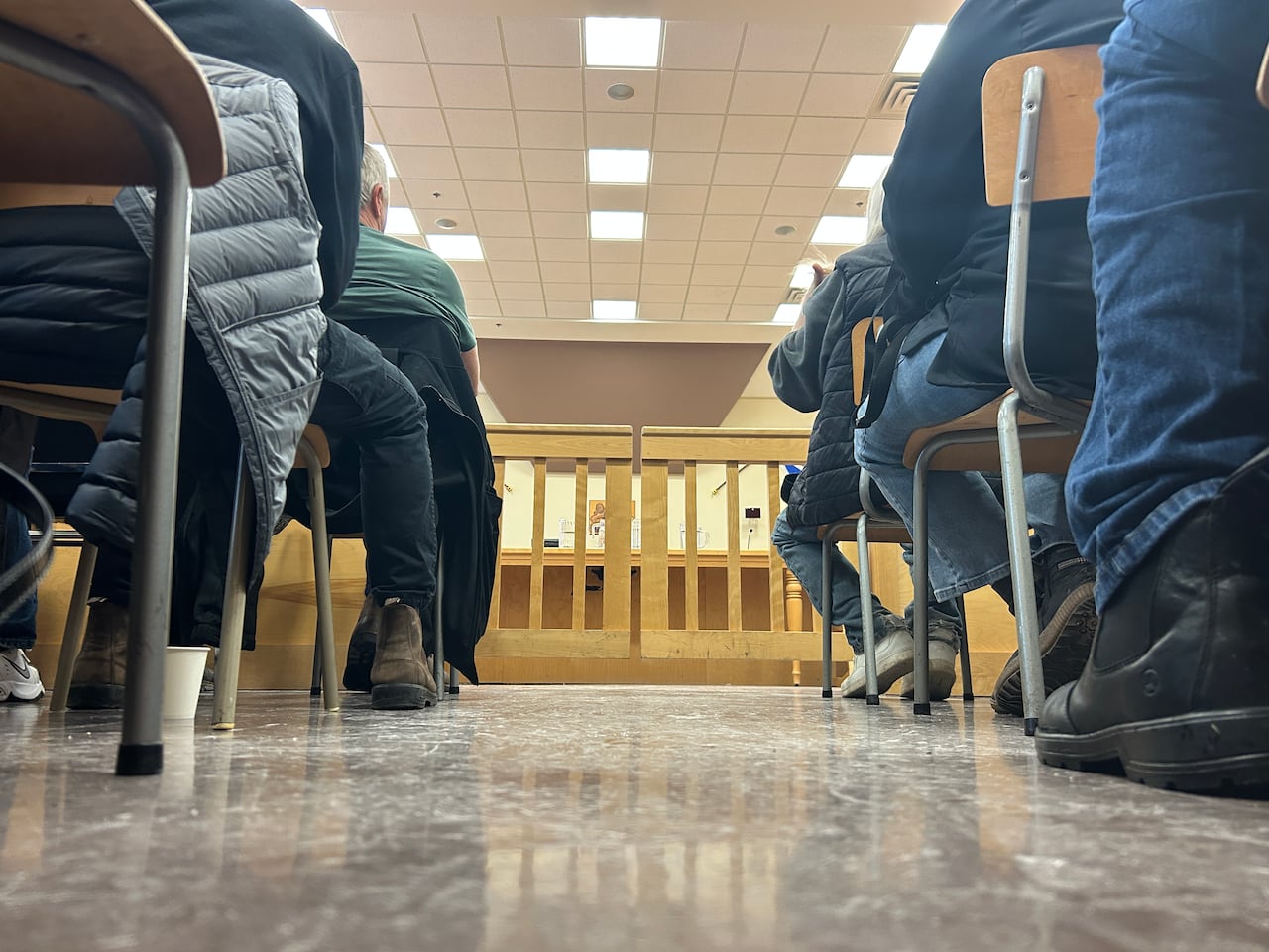 A photo of several people's feet as they're seated in a courtroom.