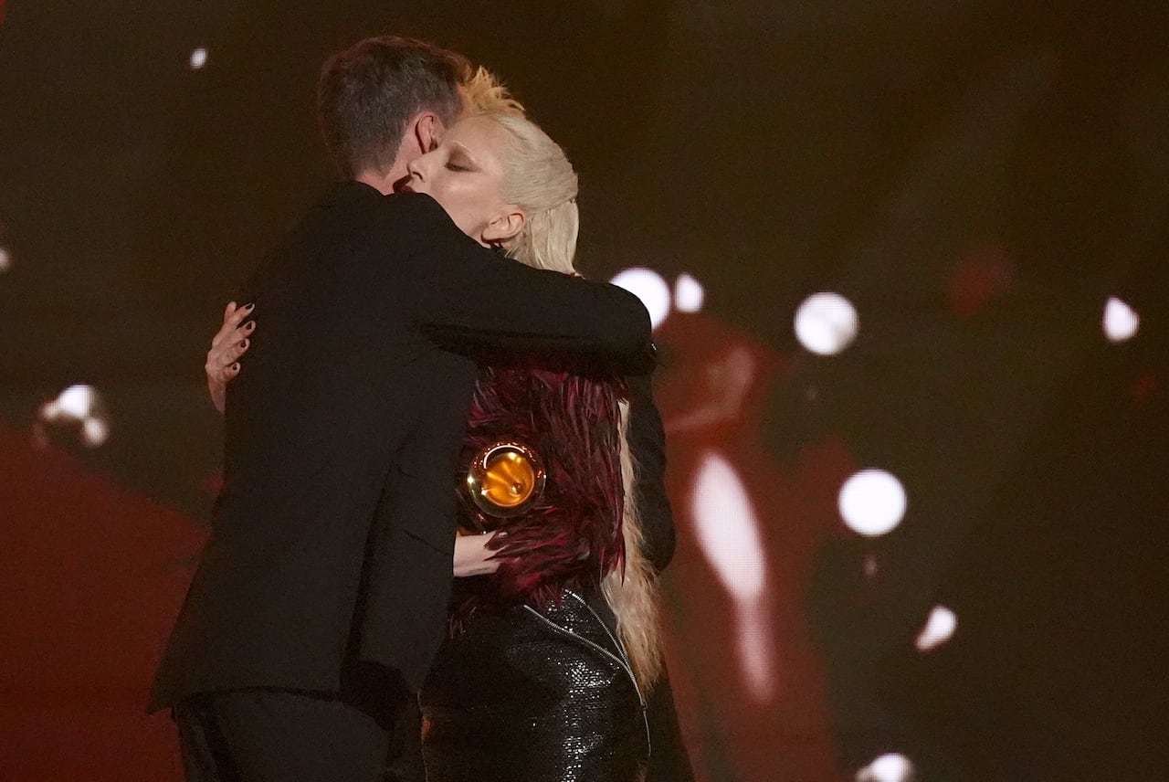 Two people embrace on stage at the Grammy Awards.