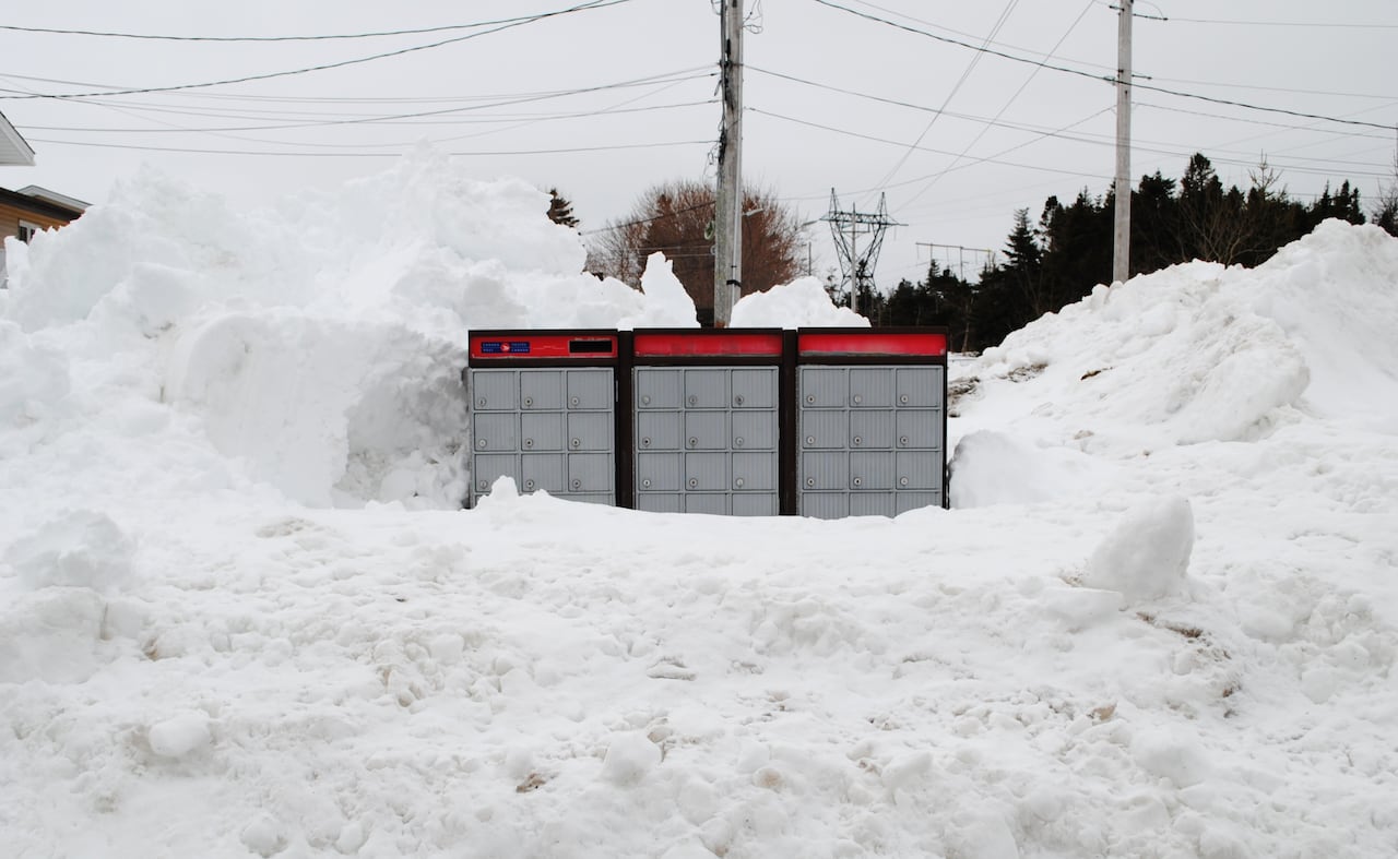 Three large community mailboxes, with several locked compartments, surrounded by huge snowbanks on all sides.