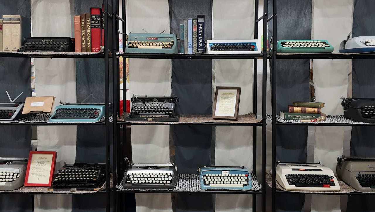 Shelves full of differently coloured typewriters. 