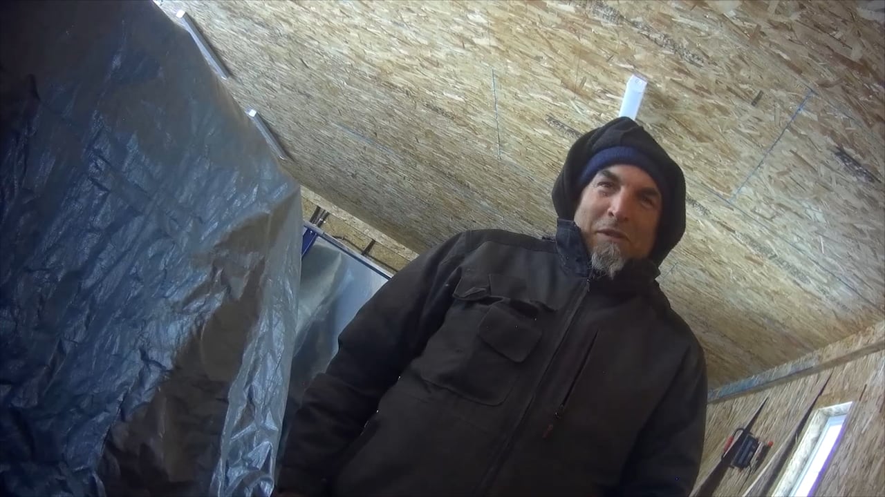 A picture of a man with a goatee wearing a hoodie in what appears to be a barn