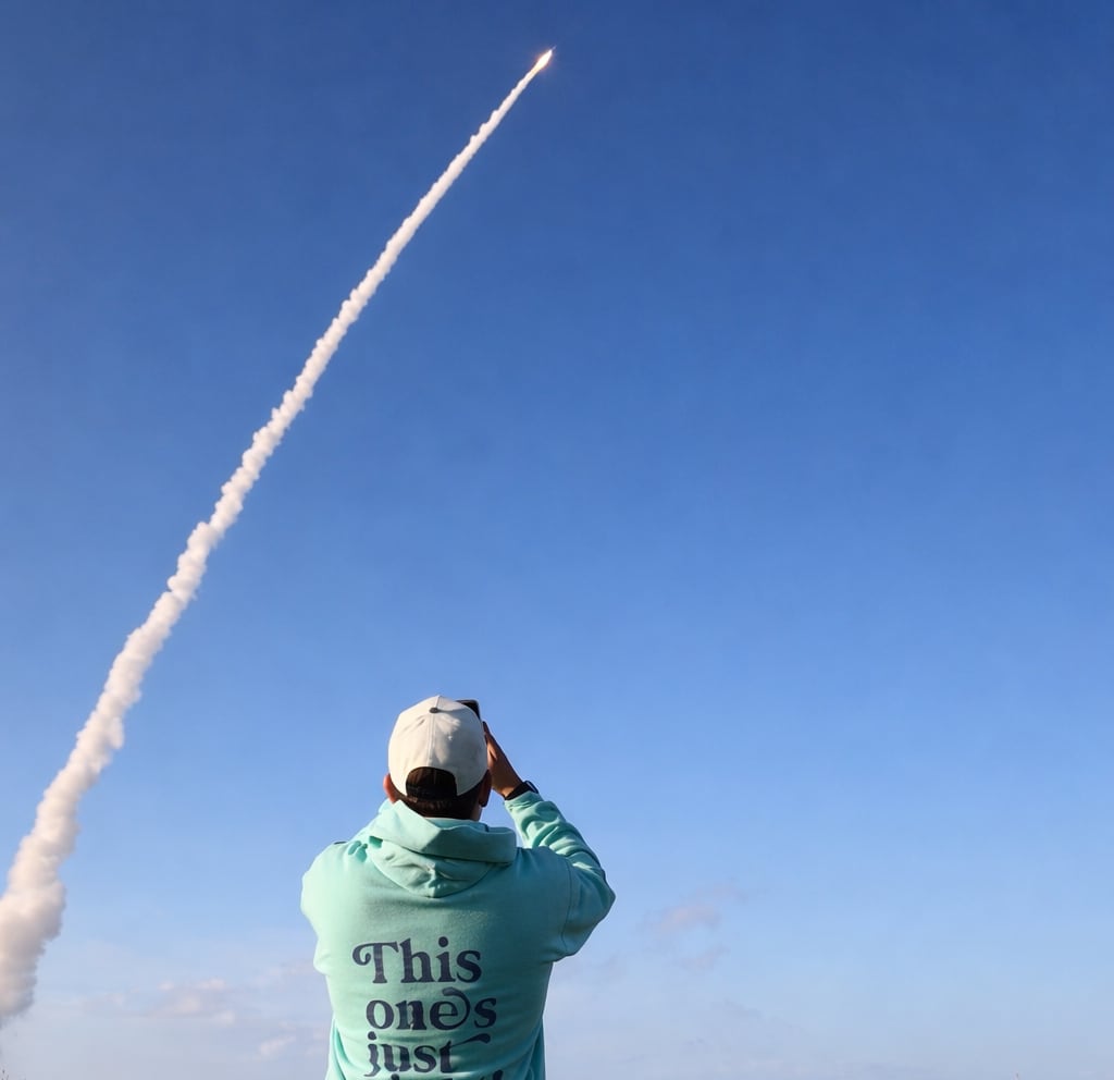 Man points phone at rocket launch 
