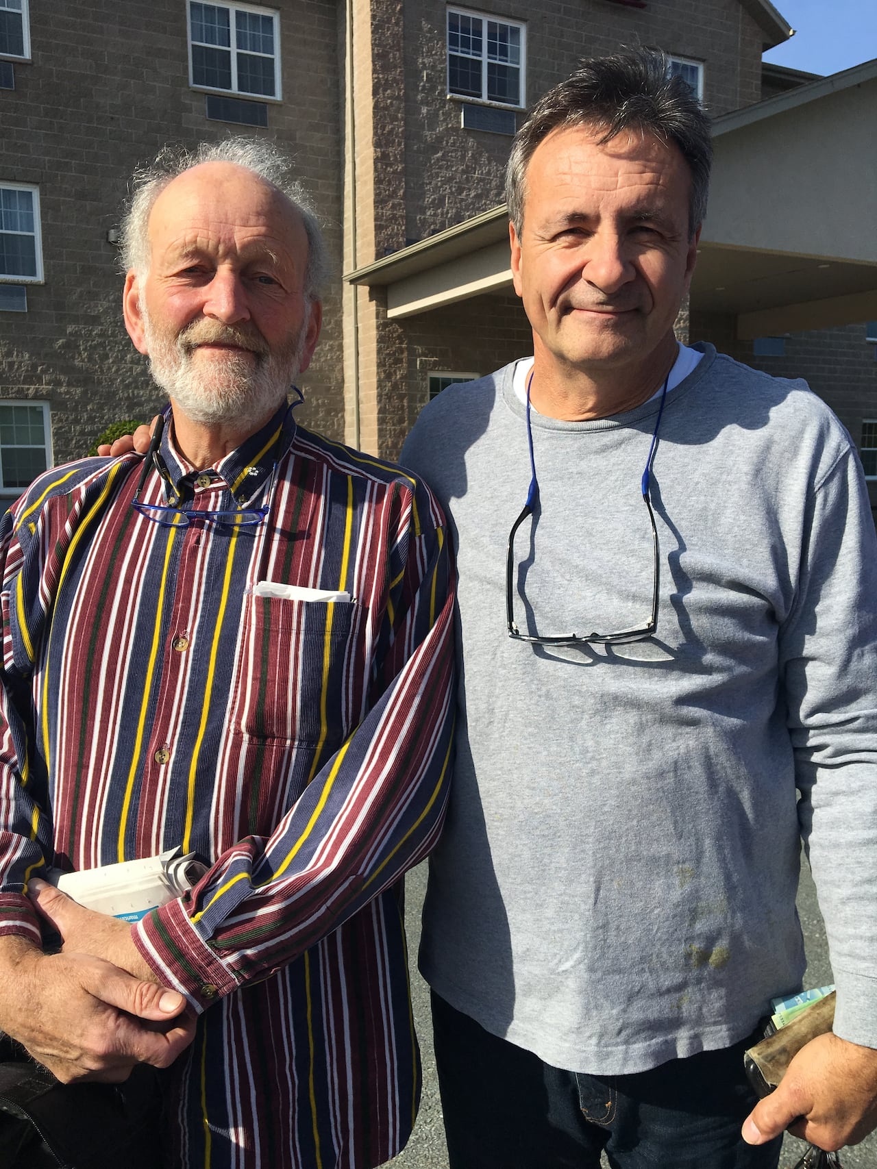 Two men, both wearing glasses around their neck, are shown in a photo.