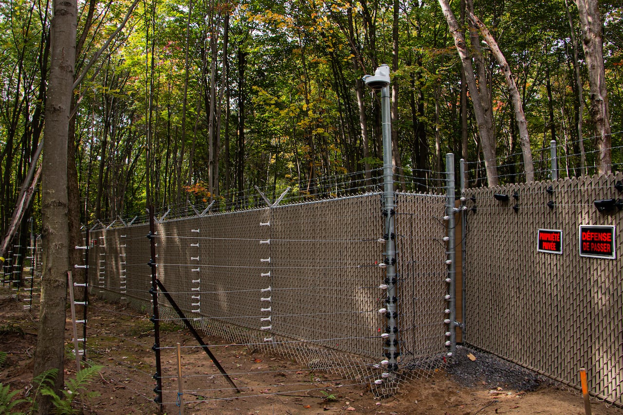 The exterior of a fence in a wooded area.