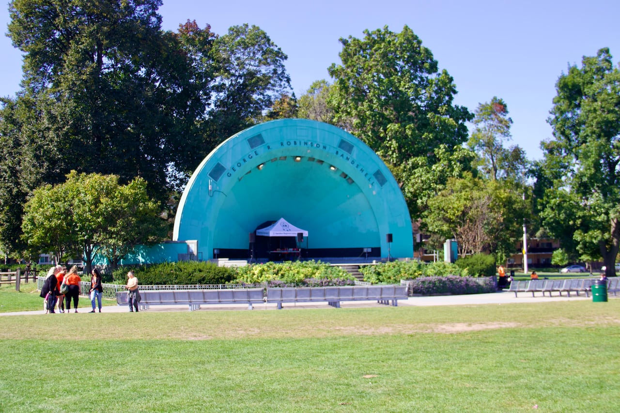 A stage at a park, people talk in the distance.