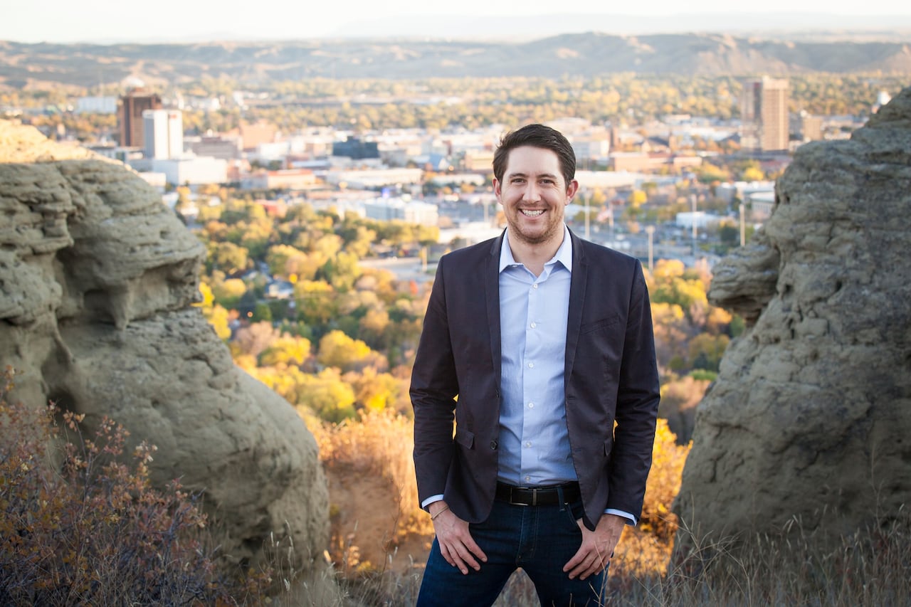 A man stands in front of a city viewscape.