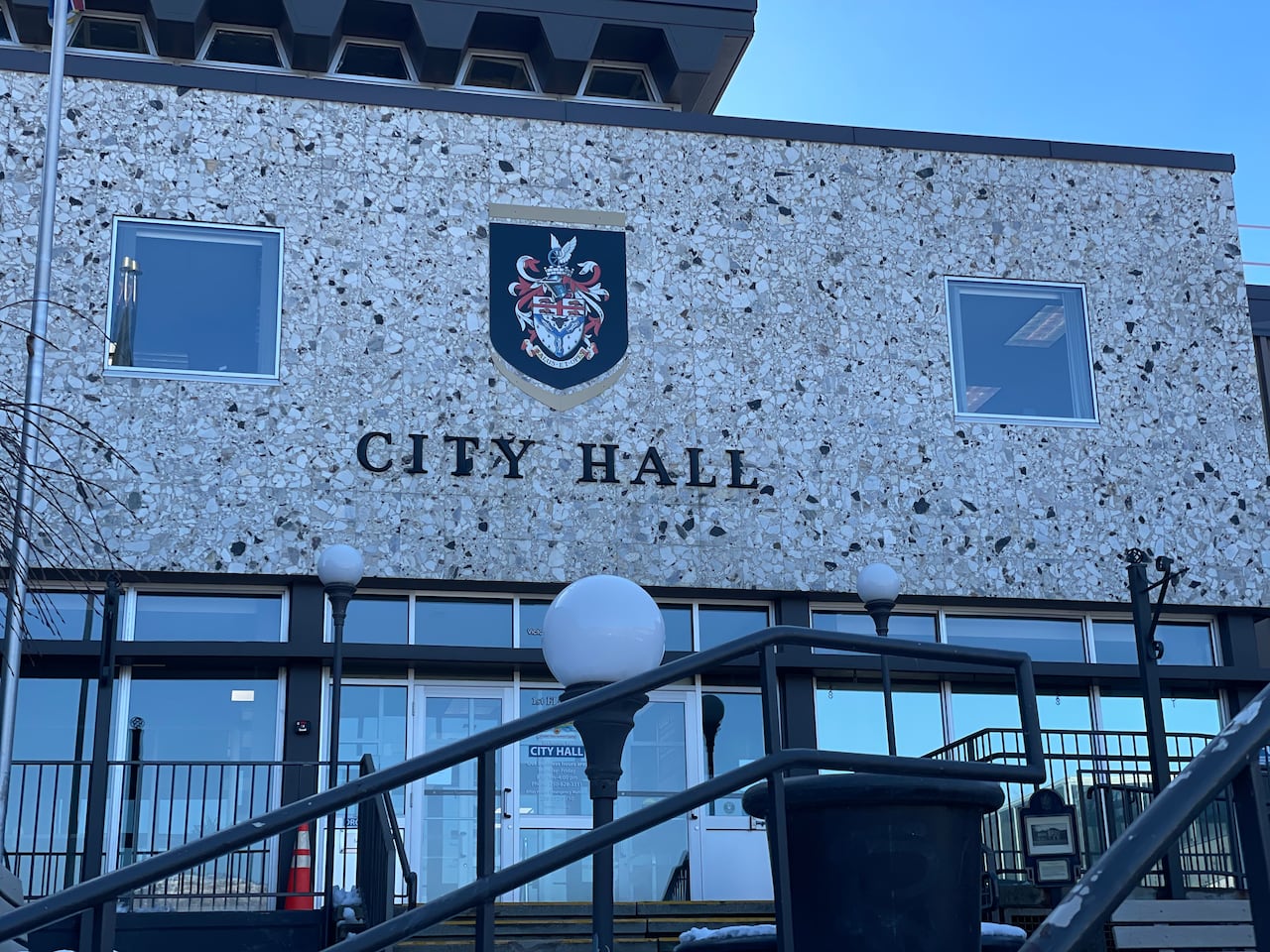 The front of a building with glass doors and windows at the bottom and the words 'City Hall' above.