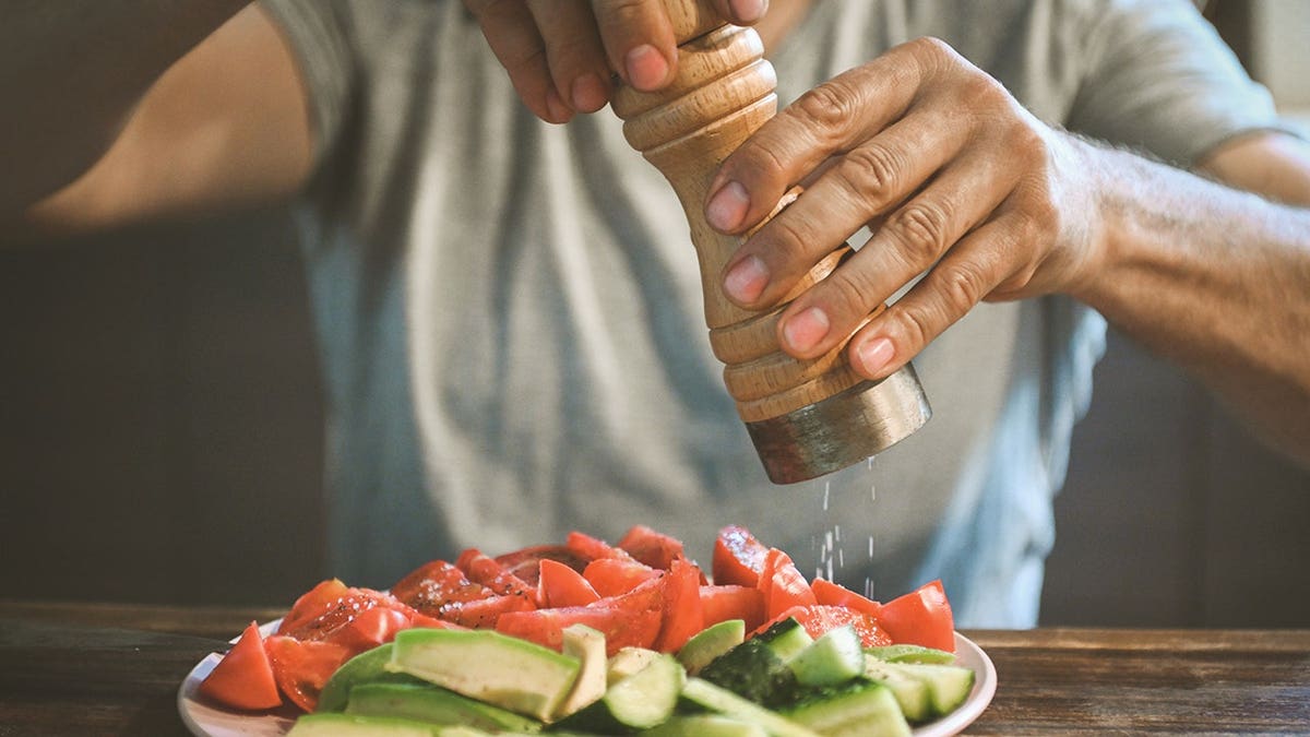 man salts fresh vegetables
