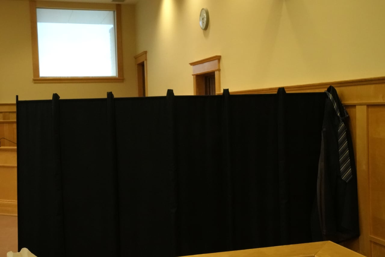 A large black curtain stands in a courtroom.