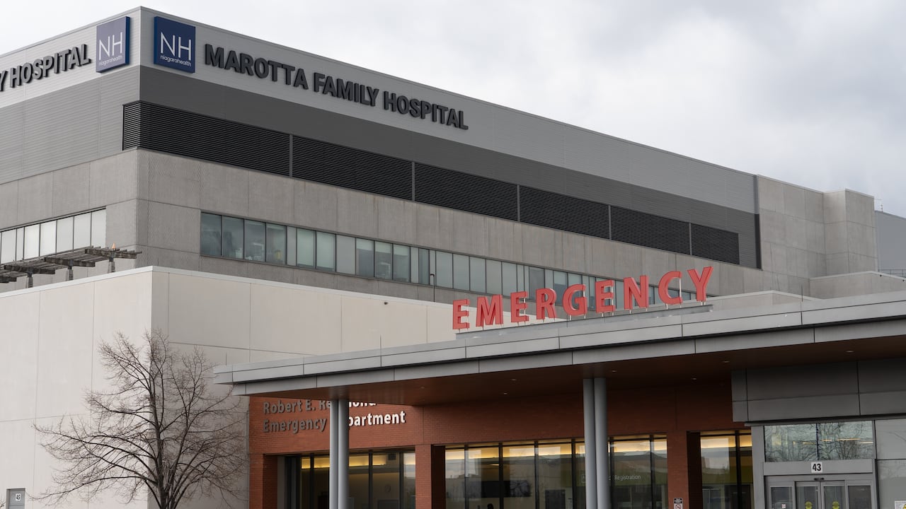 A hospital seen from street level, with block letter signs reading 'Emergency' and 'Marotta Family Hospital.'