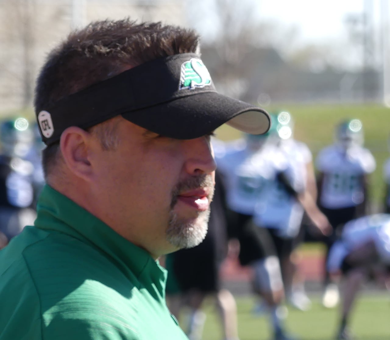 Two men in green on a football feild.