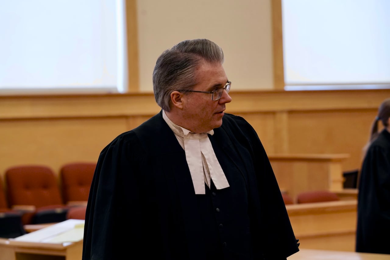 A lawyer in black robes with a white tie.
