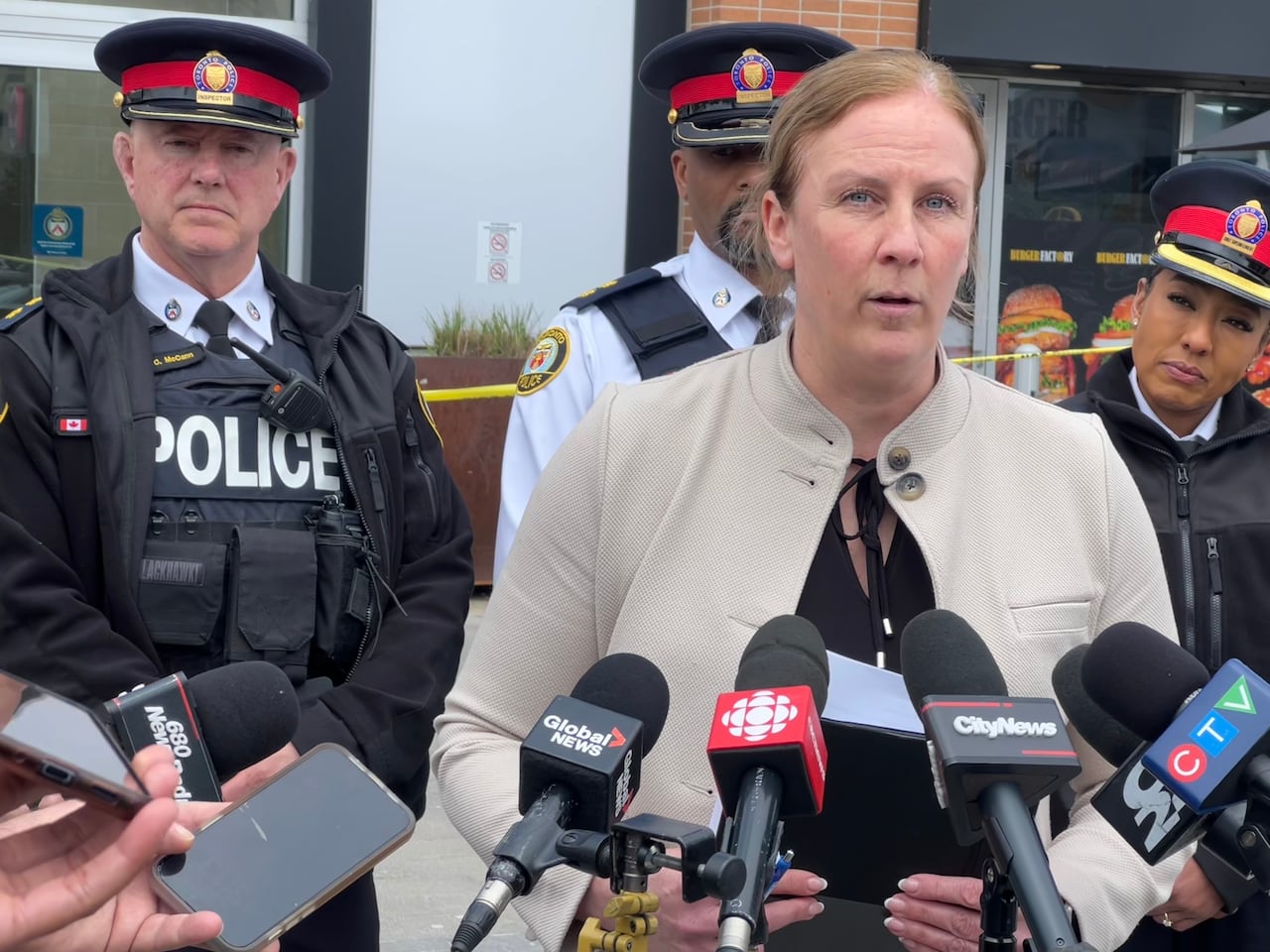 A woman speaks in front of a row of microphones.