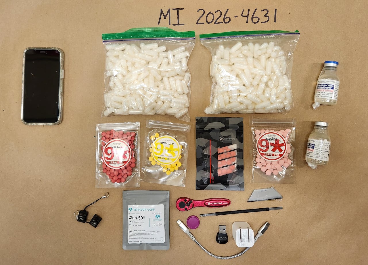 Contraband seized by police are laid out on display, including bags of pills and a phone.