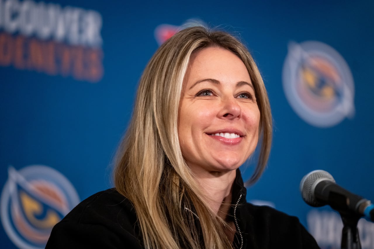 A woman smiles in front of a blue background.