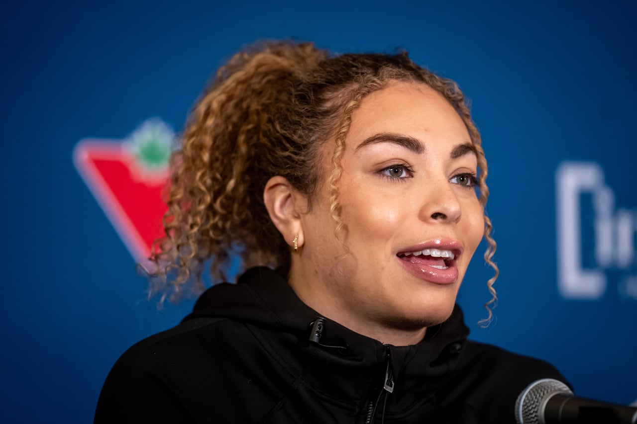A woman speaks in front of a blue background.
