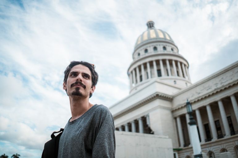 A tou guide stands outside of a domed building in Havana