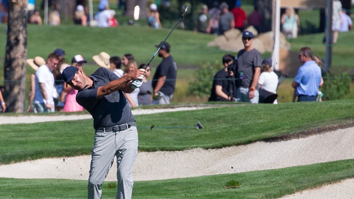 Tony Romo swinging a golf club on a golf course.