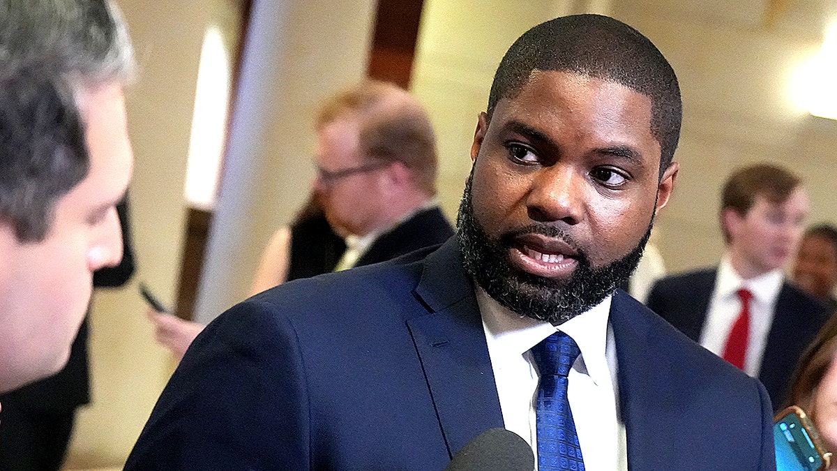 Byron Donalds speaking at a podium in a suit and tie