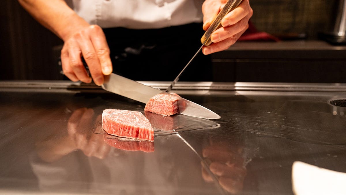 Chef slicing Kobe beef on a hotplate
