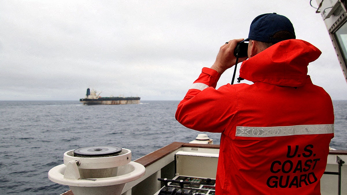 U.S. Coast Guard official looking through binoculars at a ship