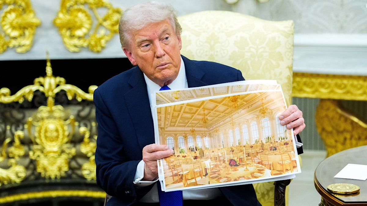 President Donald Trump holding a rendering of the planned White House Ballroom extension in the Oval Office