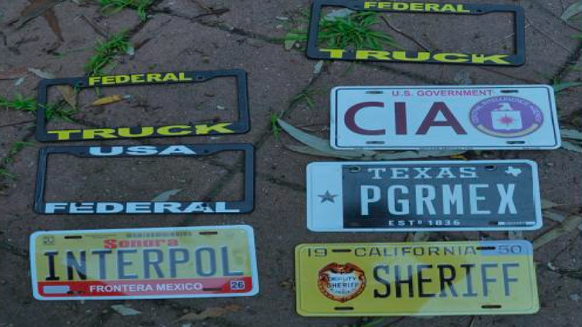 Fake law enforcement-style license plates labeled CIA, Interpol, and Sheriff shown as evidence