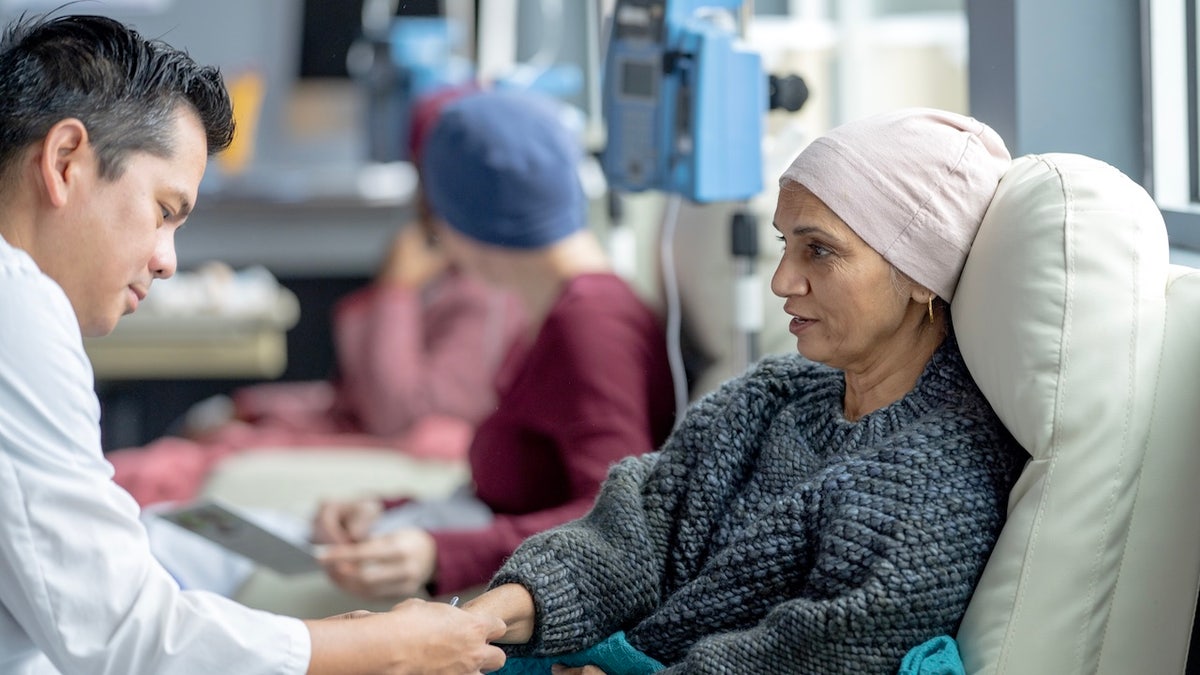 A small group of female cancer patients wearing head scarves sitting in treatment chairs in an oncology clinic