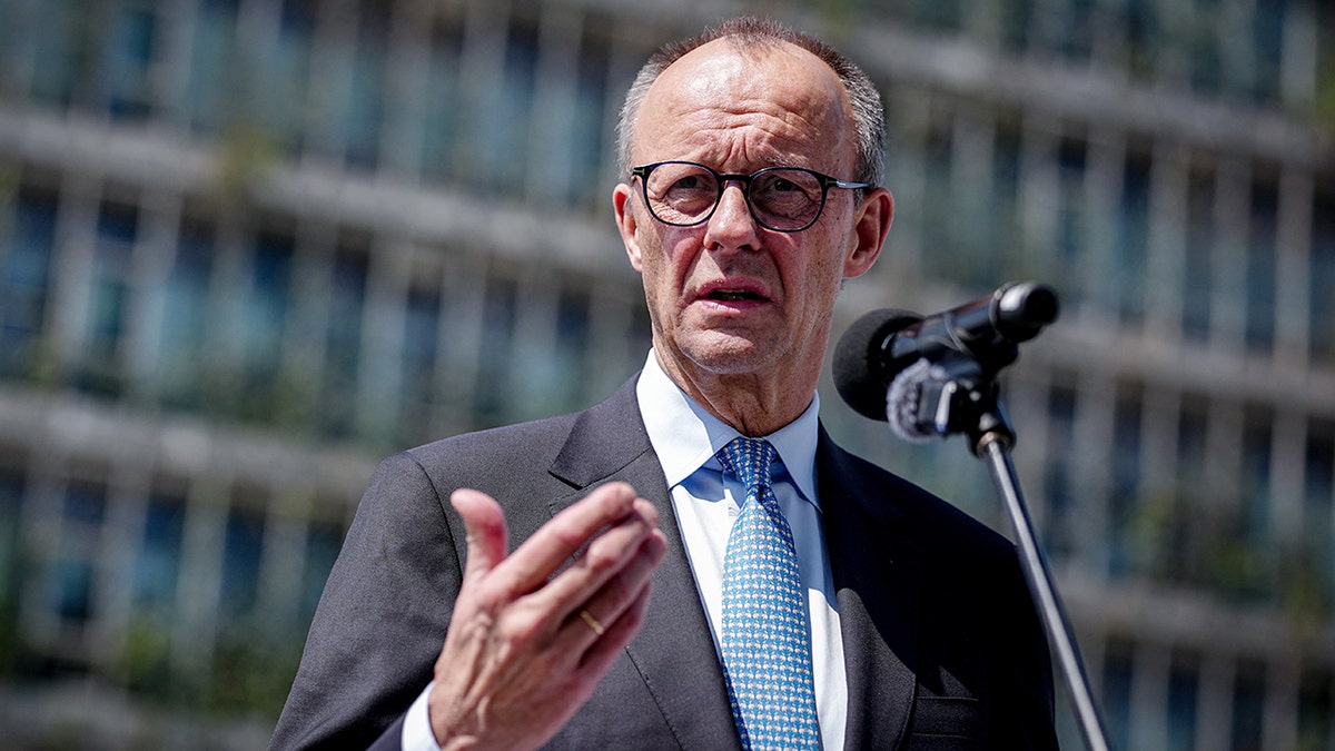 German Chancellor Friedrich Merz speaking at a podium during a trip to India