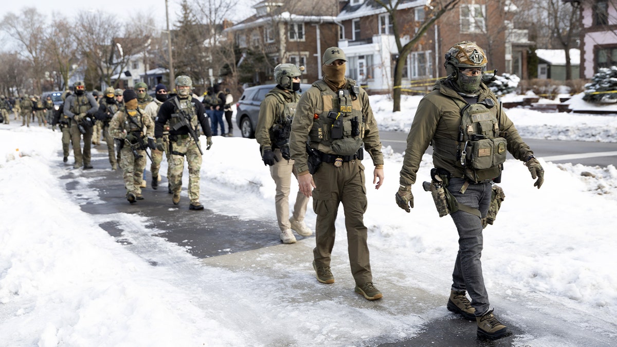 Federal agents walk on a city street in Minneapolis.