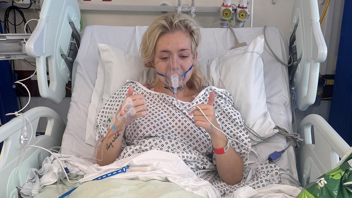 Kayley Boda giving two thumbs up as she lies in hospital bed after cancer diagnosis.