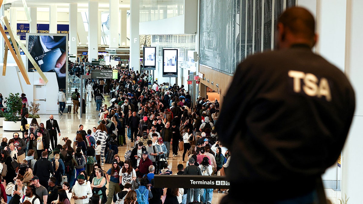 TSA agent monitors passengers at LaGuardia Airport.