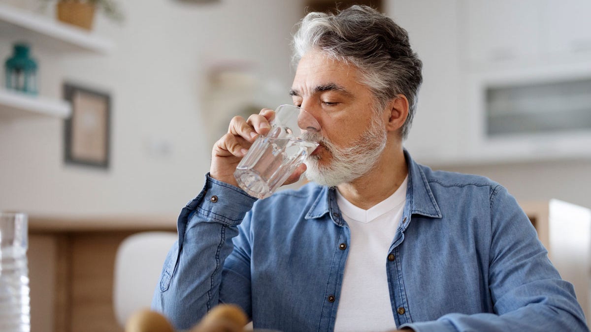 A man drinking water from a clear glass.